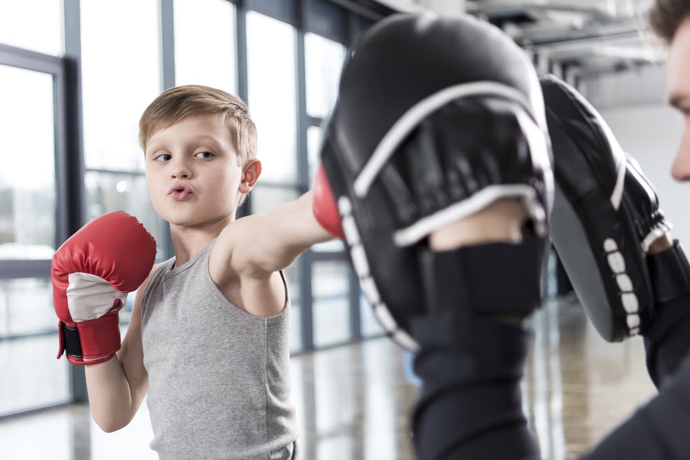 young boy boxer practicing punches with coach