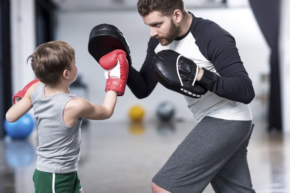 Young,Boy,Boxer,Practicing,Punches,With,Coach